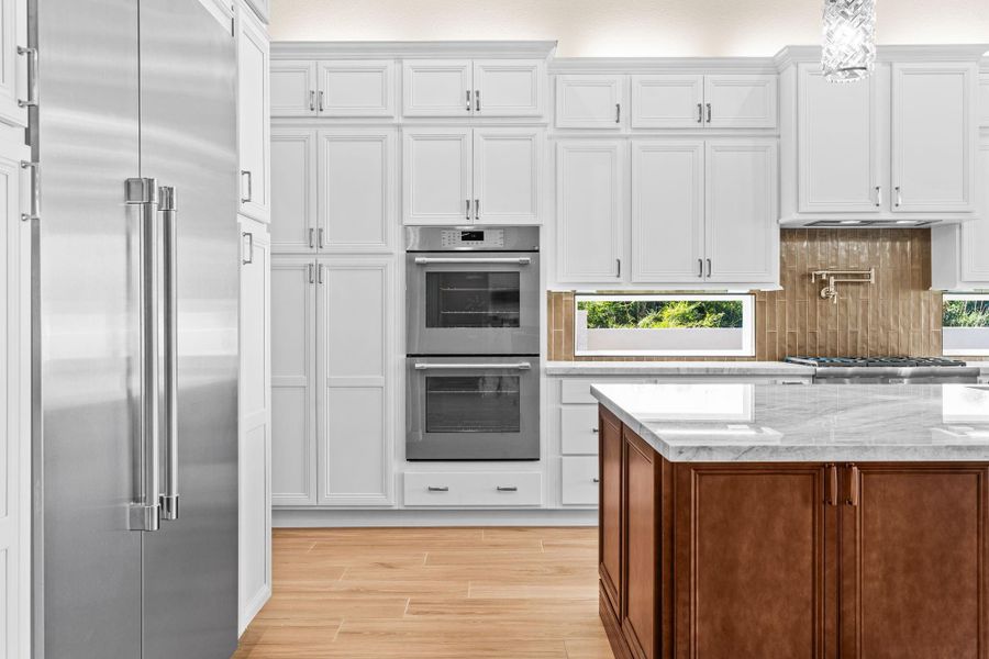 Close-up view featuring stainless appliances, double ovens, and abundant built-in storage.