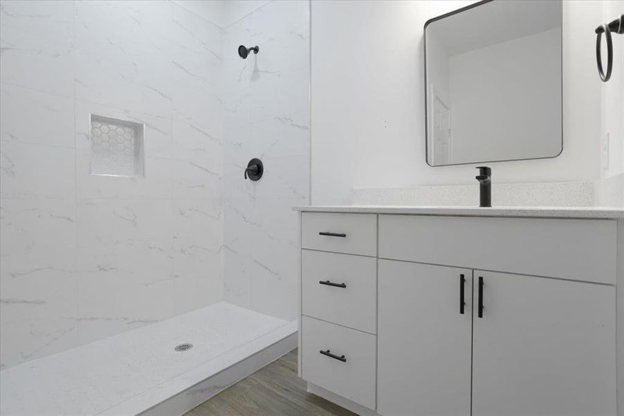 Bathroom with hardwood / wood-style floors, vanity, and a tile shower