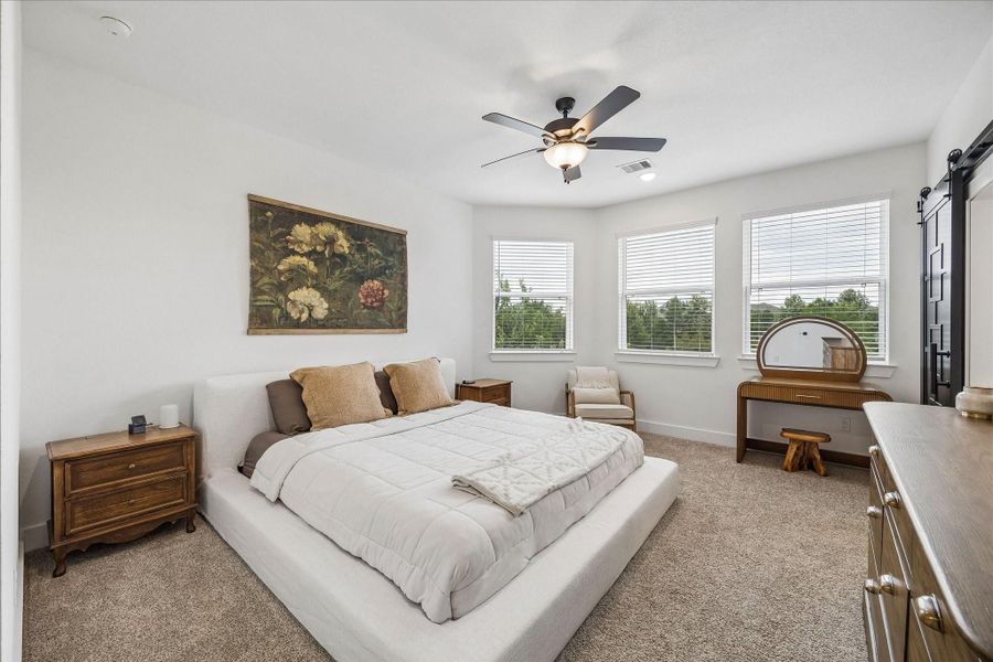 Retreat to the spacious primary suite, filled with natural light from stunning windows and offering plenty of room to unwind. An ornate sliding door leads to the beautifully appointed primary bathroom.