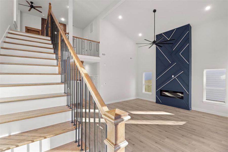 Stairs featuring hardwood / wood-style flooring, ceiling fan, and high vaulted ceiling