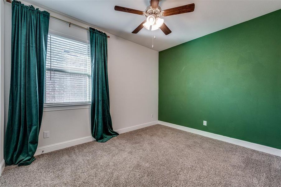 Carpeted spare room featuring a ceiling fan.