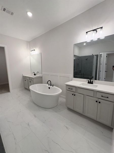 Freestanding soaking tub with matte black fixtures, dual vanity sinks, white stone countertops, and tile flooring Freestanding soaking tub with matte black fixtures, dual vanity sinks, white stone countertops, and tile flooring