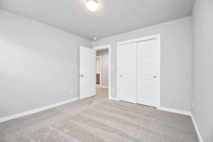 Secondary bedroom features plush carpeting, large windows that let in plenty of natural light, bright paint, and spacious closets. Sample photo of completed home with similar floor plan. Actual colors and selections may vary.