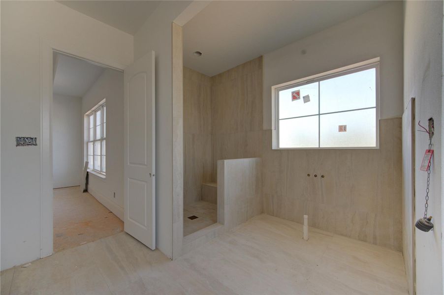 Future spa-inspired primary bathroom currently under construction featuring oversized tile selections, a walk-in shower, elevated ceiling heights, and a spacious layout designed for luxury and comfort.
