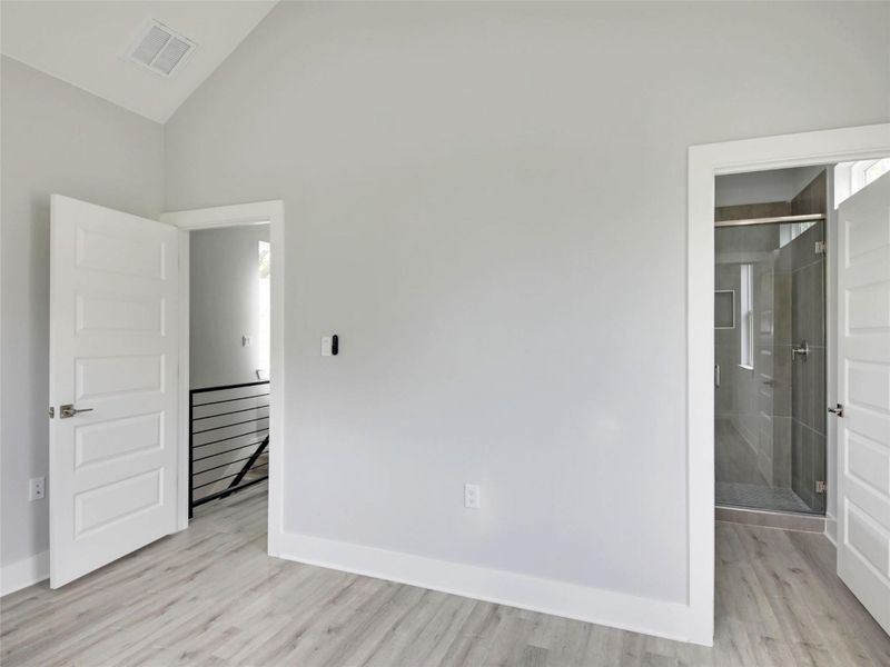 Empty room with light wood-style flooring and vaulted ceiling