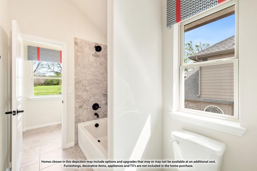 Bathroom with white soaking tub, gray tile surround, black fixtures, and two windows with natural light