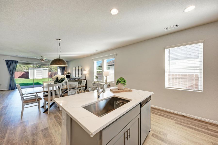 Kitchen with gray cabinets, a kitchen island, light stone counters, light wood-type flooring, and stainless steel dishwasher