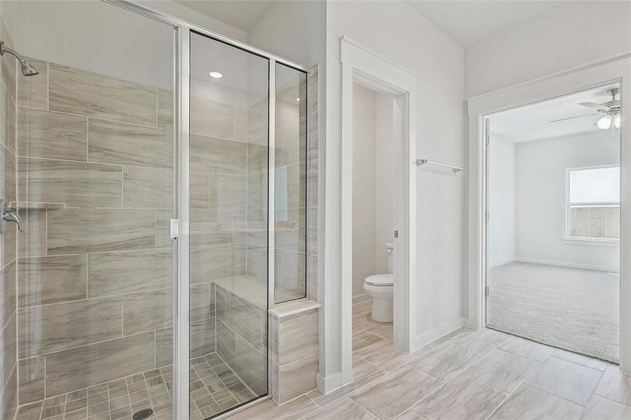 Bathroom featuring toilet, walk in shower, and tile patterned floors