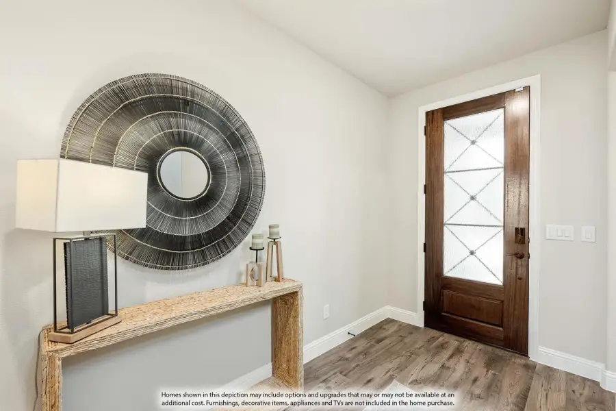 Home entryway with wood front door, glass panels, hardwood floors, and console table with decorative mirror