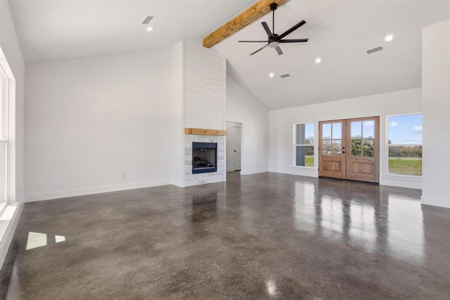 Spacious living area featuring polished concrete floors, a fireplace with a wood mantel, and large windows offering scenic views