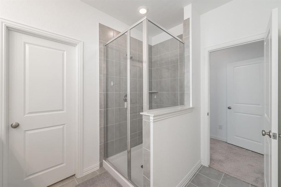 Bathroom with a shower stall and light tile patterned floors