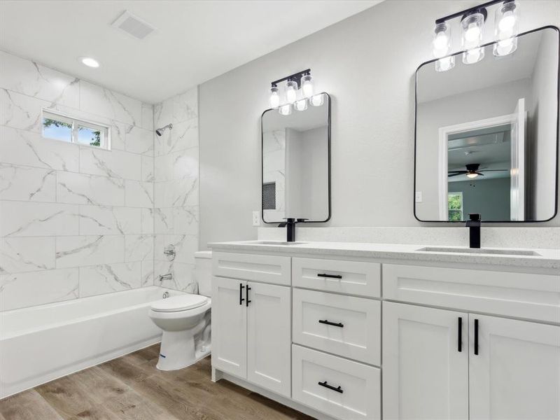 Full bathroom featuring oversized vanity, ceiling fan, toilet, hardwood / wood-style flooring, and tiled shower / bath combo