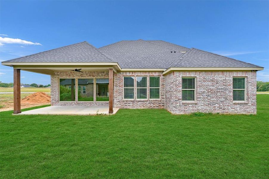 Rear view of house with a patio, ceiling fan, and a yard