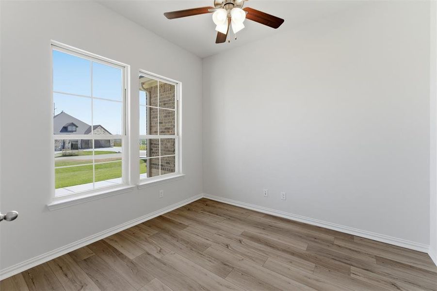 Room featuring a ceiling fan with light fixture, wood-finish flooring, and white baseboards