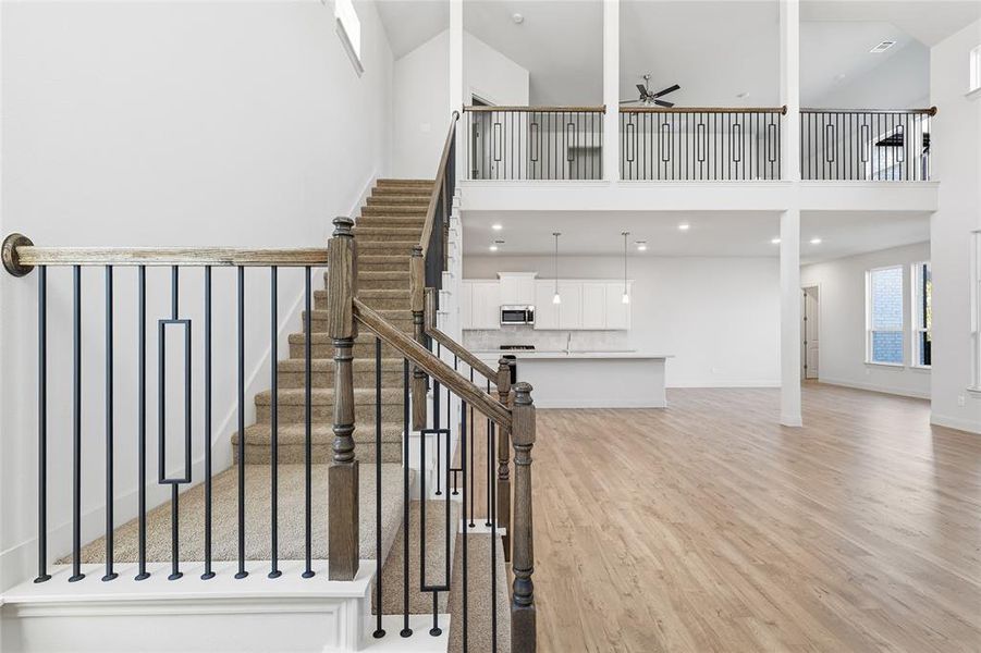 Staircase with wood finished floors, a ceiling fan, a towering ceiling, and recessed lighting
