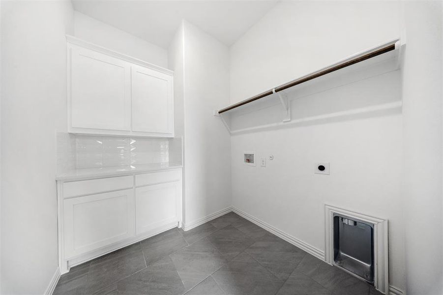 Laundry area with hookup for a gas dryer, washer hookup, electric dryer hookup, and dark tile patterned floors Laundry area with hookup for a gas dryer, washer hookup, electric dryer hookup, and dark tile patterned floors