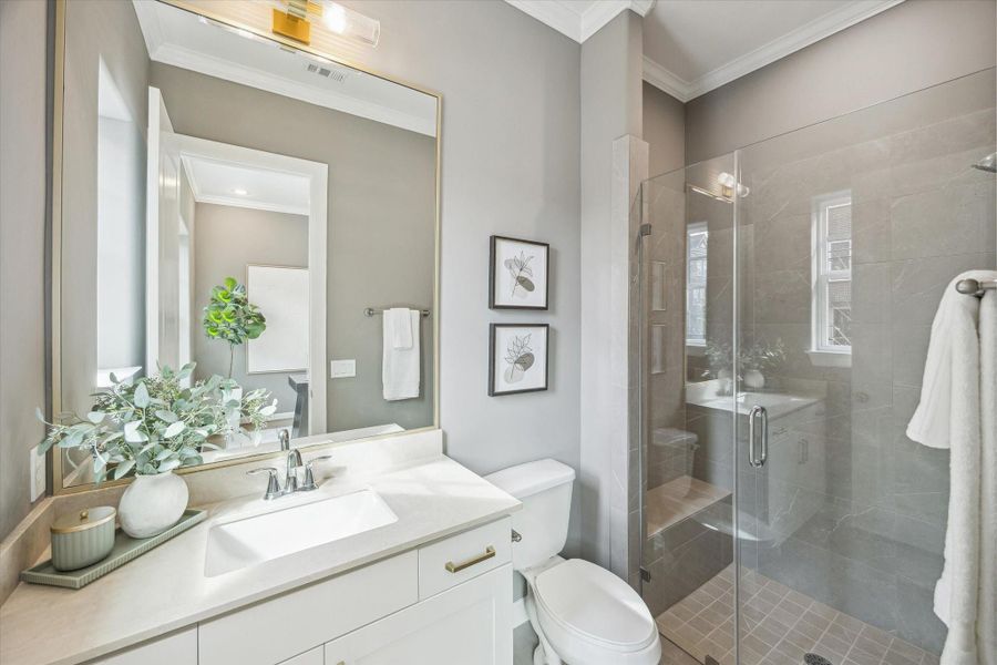 En-suite bath #3 offers frameless shower, limestone countertop, and frameless gold mirror.