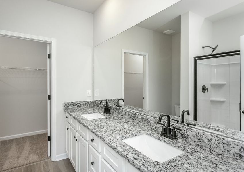 This bathroom has dual sinks and a glass-enclosed shower