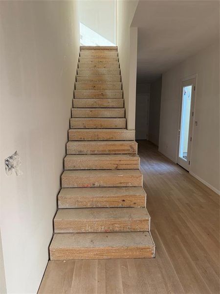 Stairs featuring wood finished floors and baseboards Stairs featuring wood finished floors and baseboards