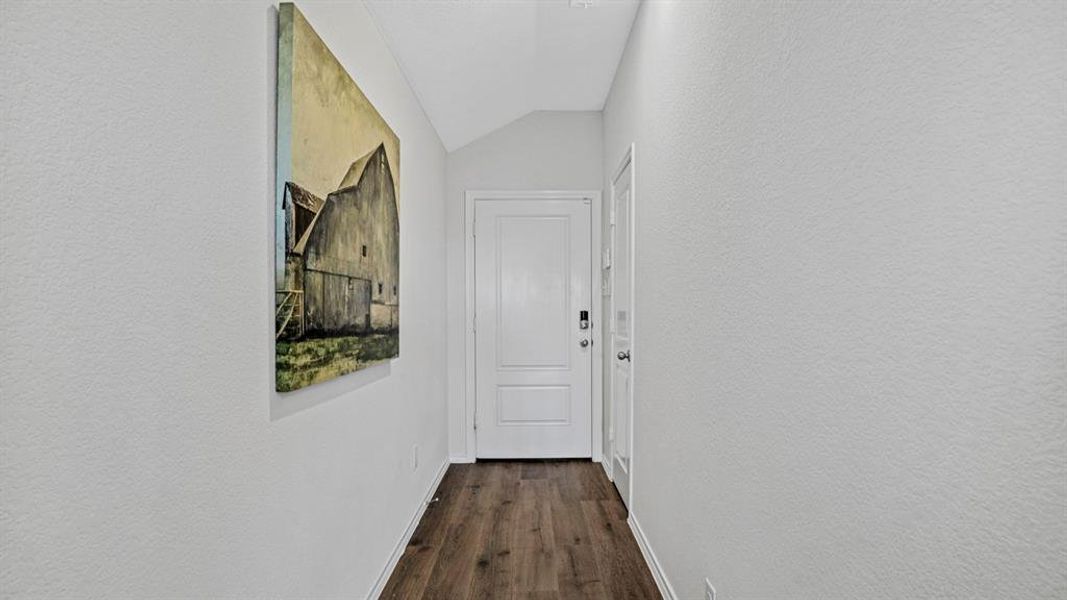 Entryway featuring wood-finish flooring, a white paneled door with hardware, textured walls, and a recessed ceiling light