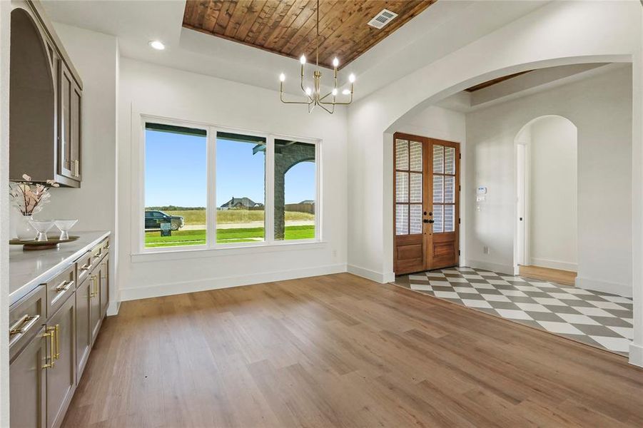 Unfurnished dining area with light wood-type flooring, french doors, healthy amount of natural light, a raised ceiling, and recessed lighting Unfurnished dining area with light wood-type flooring, french doors, healthy amount of natural light, a raised ceiling, and recessed lighting
