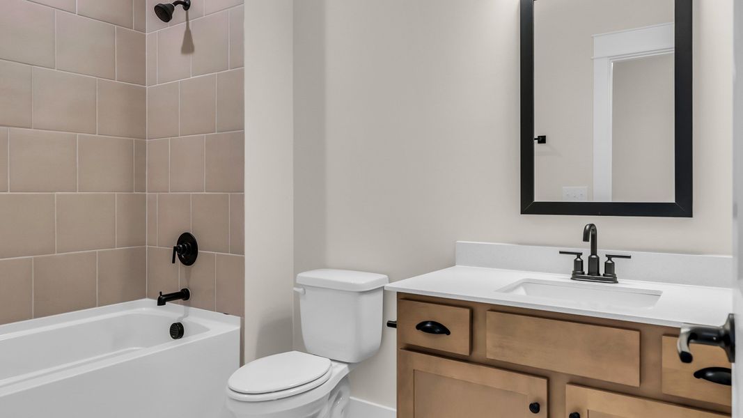 Secondary bathroom with vanity and tiled shower (Representative of finished home)