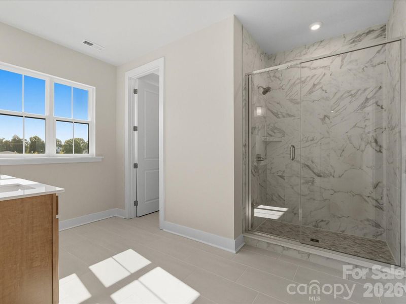 Dual vanity primary bathroom with tiled walk-in shower