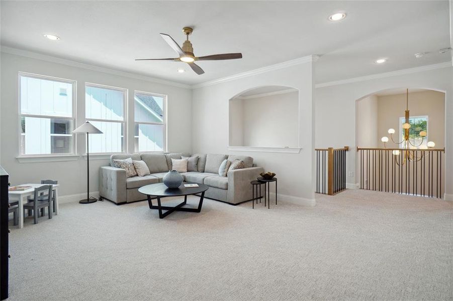 Living room with ornamental molding, carpet flooring, and ceiling fan with notable chandelier