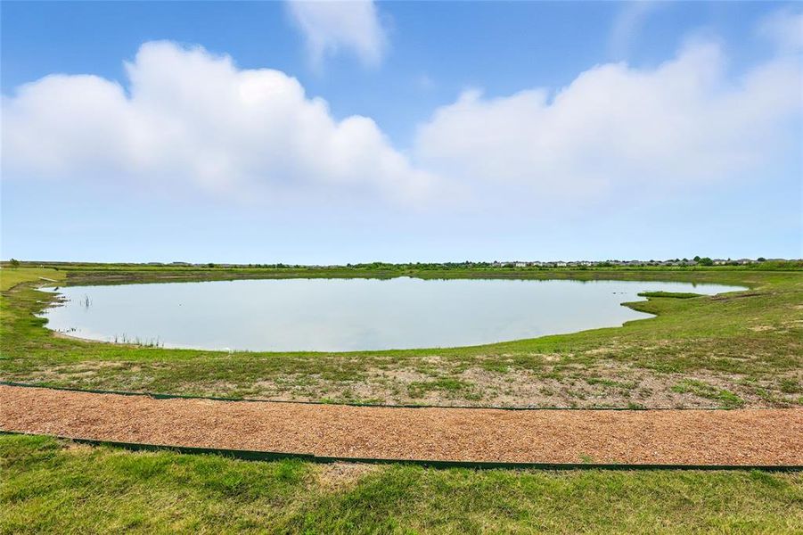 Expansive body of water bordered by natural green space and a walking path