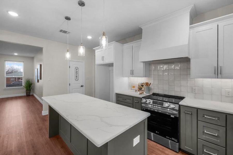 Kitchen with premium range hood, gray cabinetry, white cabinets, stainless steel range with electric cooktop, and a center island