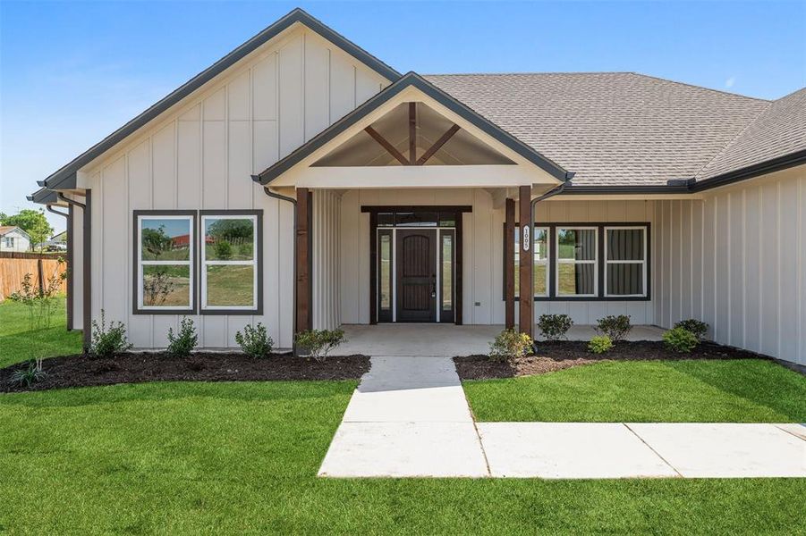 View of front of home featuring roof with shingles, fence, board and batten siding, and a front yard