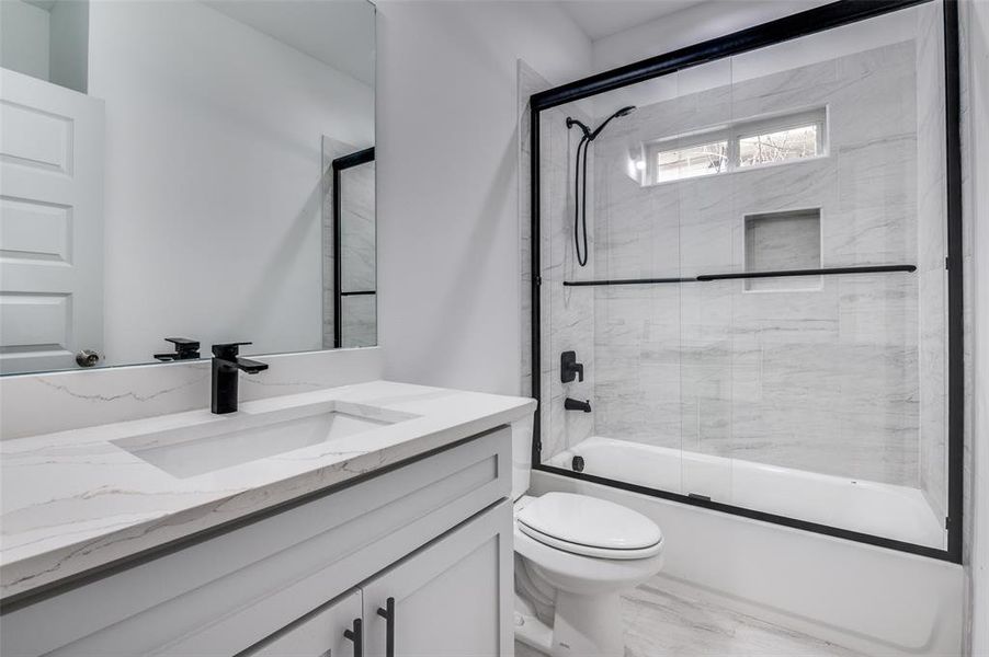 Bathroom with vanity, toilet, and shower / bath combination with glass door