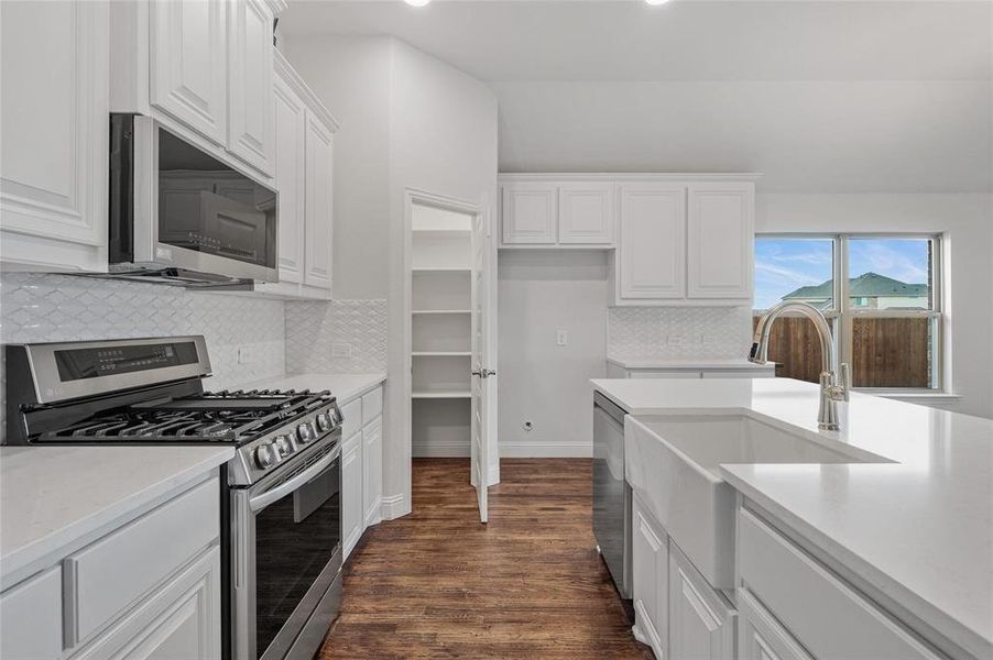 Kitchen featuring stainless steel appliances, white cabinets, dark wood finished floors, and recessed lighting