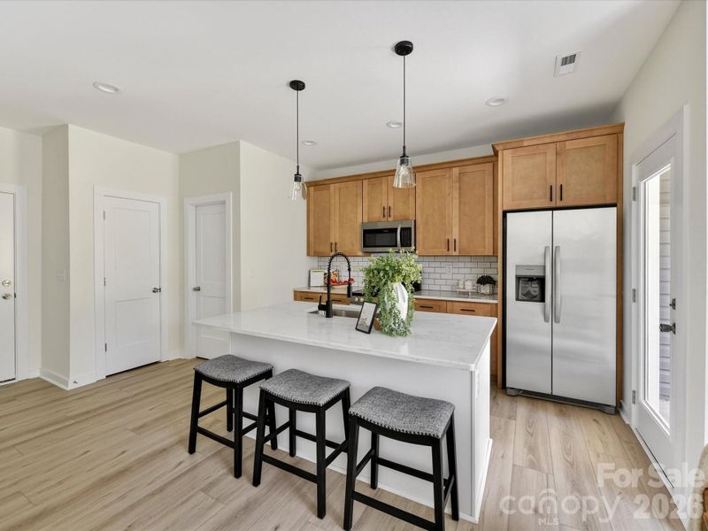 Stylish open-concept kitchen featuring granite countertops, stainless steel appliances, subway tile backsplash, and a spacious island with seating, perfect for everyday living and entertaining. Stylish open-concept kitchen featuring granite countertops, stainless steel appliances, subway tile backsplash, and a spacious island with seating, perfect for everyday living and entertaining.