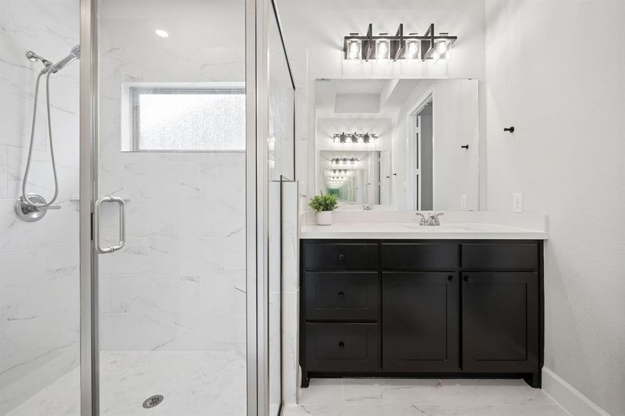 Modern bathroom featuring a glass-enclosed shower with white tiled walls and floor, a rectangular frosted window, a dark wood-finish vanity with ample storage, a white countertop, and a contemporary light fixture
