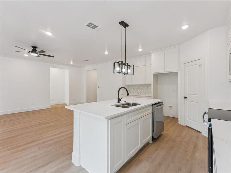 Kitchen featuring light wood-type flooring, a center island with sink, decorative light fixtures, white cabinets, and recessed lighting