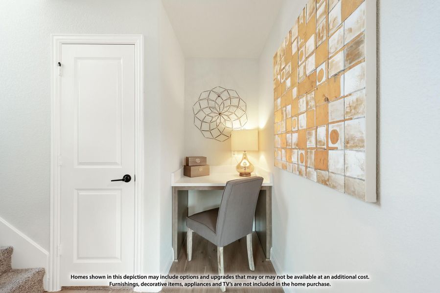 Small built-in desk nook with gray chair, lamp, and wall art near a white door and hardwood floors Small built-in desk nook with gray chair, lamp, and wall art near a white door and hardwood floors