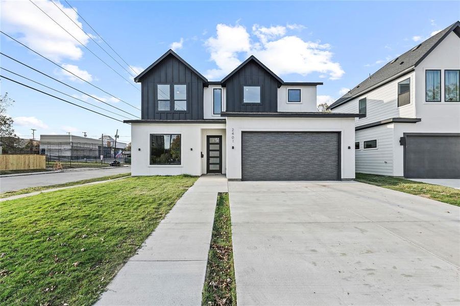 Modern farmhouse with driveway, stucco siding, a front yard, an attached garage, and board and batten siding