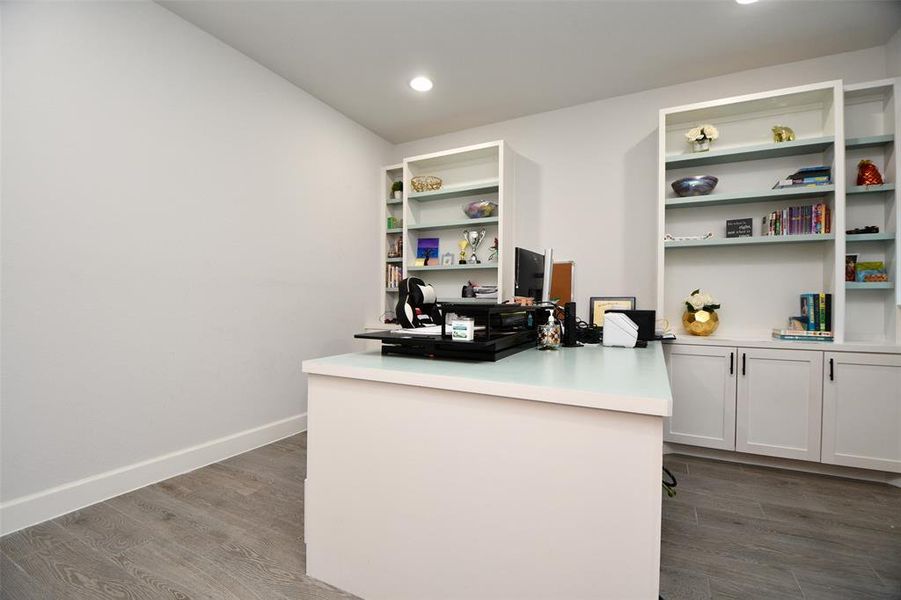 This photo showcases a modern home office with built-in shelves, a spacious desk, and ample storage. The room has a clean, minimalist design with neutral tones, making it a flexible space for work or study.