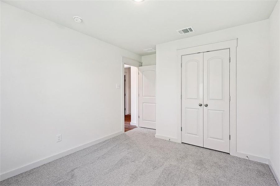 Unfurnished bedroom with light carpet and a closet