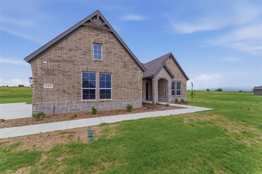 Brick and stone exterior featuring an arched entry, gabled rooflines, and multiple window styles