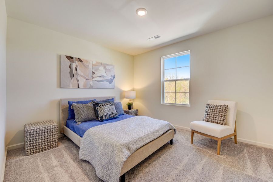 A bedroom with a bed and a chair.