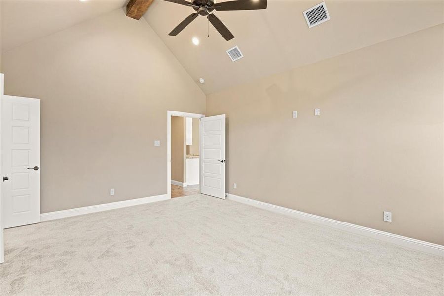 Carpeted empty room featuring beam ceiling, high vaulted ceiling, and ceiling fan