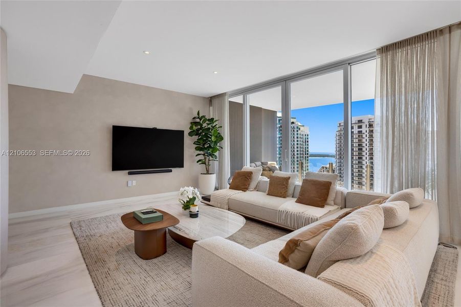 Floor-to-ceiling glass windows, recessed lighting, neutral wall finishes, and wood-finish flooring