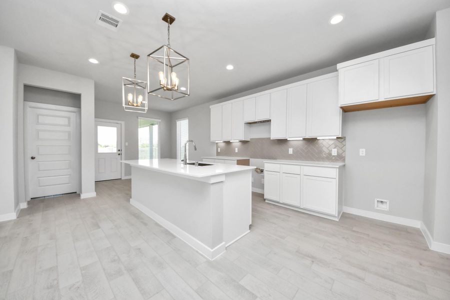 The kitchen is a culinary haven, featuring granite countertops, a tile backsplash, stainless steel appliances, 42” upper cabinets, and undercabinet lighting. Sample photo of completed home with similar floor plan. Actual colors and selections may vary.