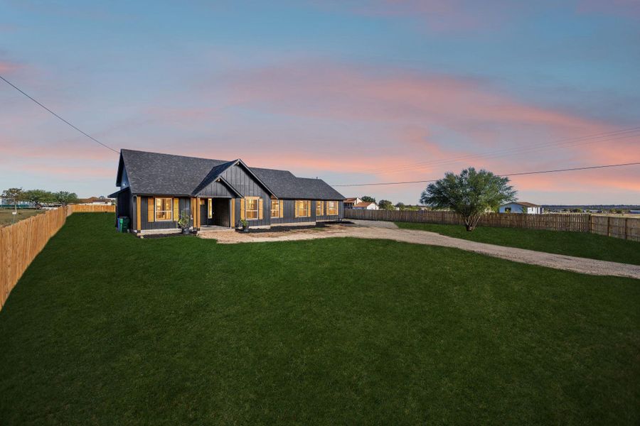 Modern inspired farmhouse featuring a fenced backyard, a porch, driveway, and board and batten siding Modern inspired farmhouse featuring a fenced backyard, a porch, driveway, and board and batten siding