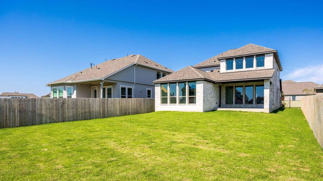 Back of property with roof with shingles, a fenced backyard, brick siding, and a patio area