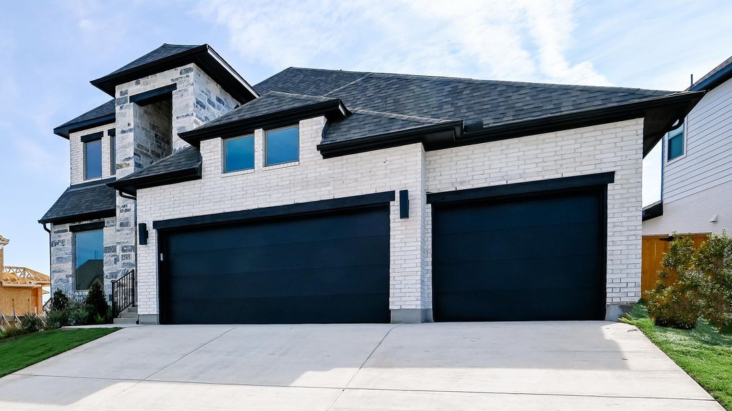 View of front of property with driveway, brick siding, and a garage