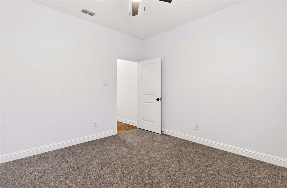 Unfurnished room with dark colored carpet and ceiling fan