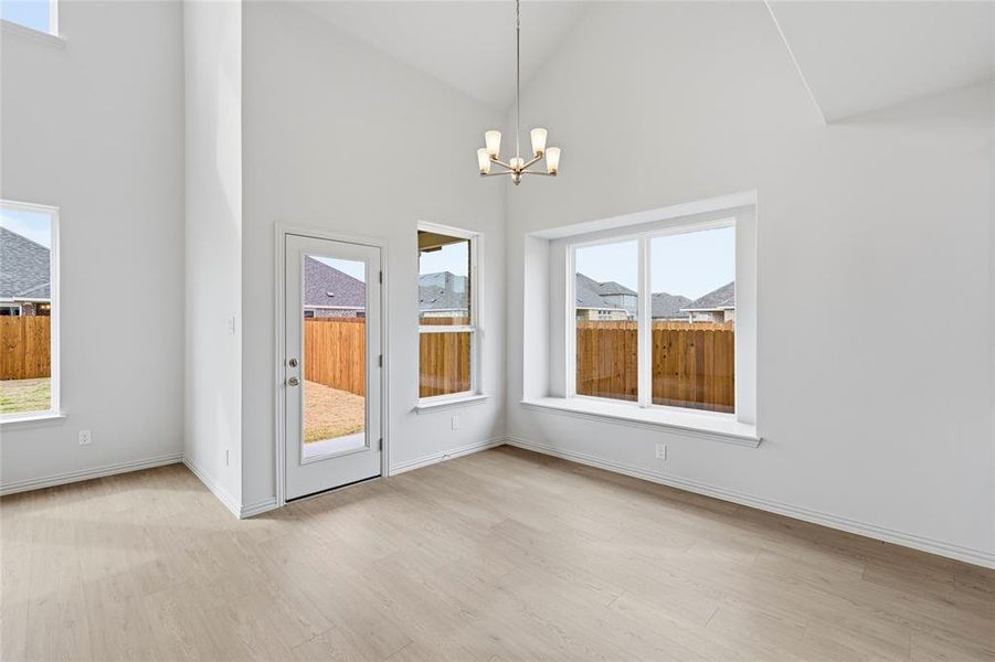 Unfurnished dining area with hanging lights, light wood-type flooring, and lofted ceiling